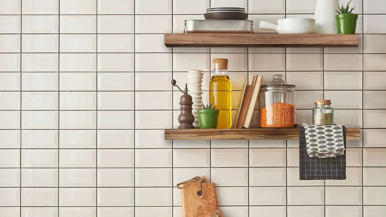 Two floating shelves in a kitchen with dishes and cooking ingredients sitting on them
