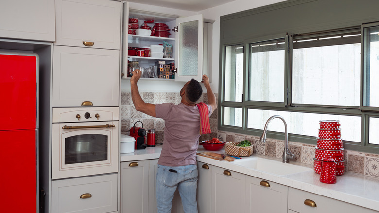 A person opening a cabinet in an organized kitchen