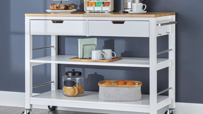 Trinity's 48-inch kitchen cart in white with a bamboo top standing against a blue wall