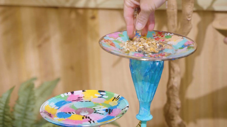 A glassware bird feeder painted in multiple colors