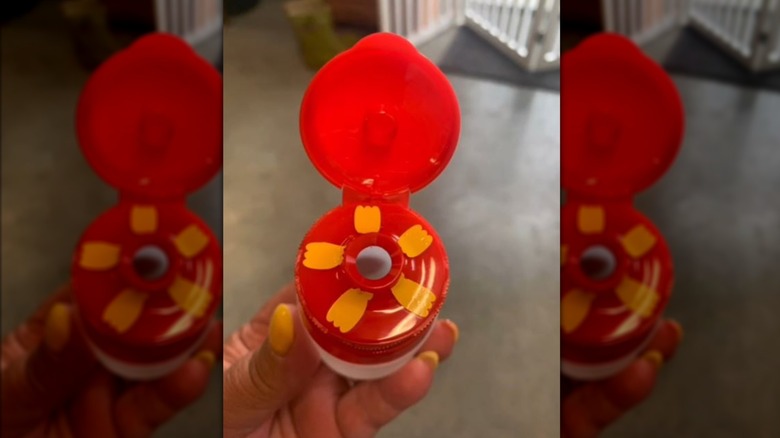 Travel dressing container with red top decorated to look like flower with yellow petals