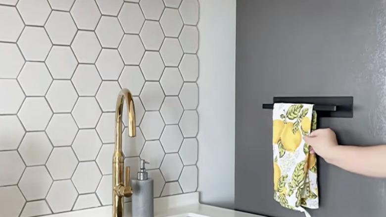 Towel bar on side of fridge in kitchen, holding lemon-themed dish towel
