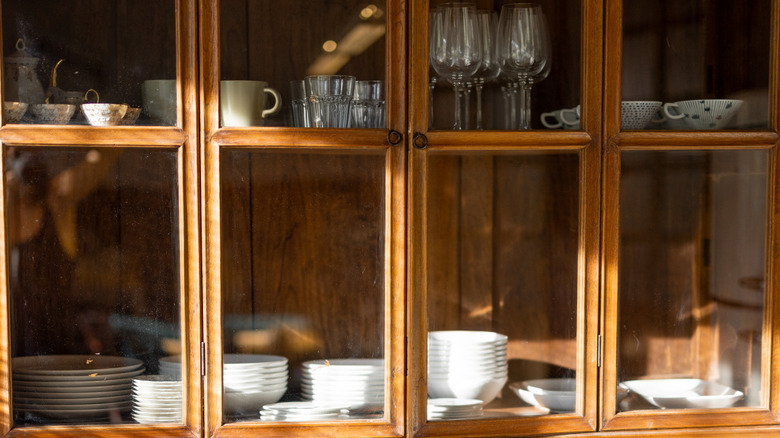Vintage wood glass front cabinets, in which dishware is displayed and stored.