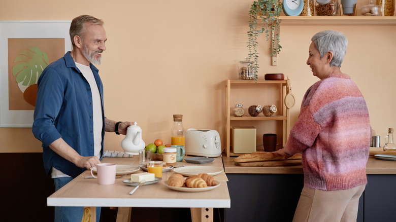 Two older people preparing breakfast at a kitchen peninsula