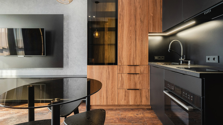 Modern kitchen with black appliances and integrated heavily grained wood cabinets.