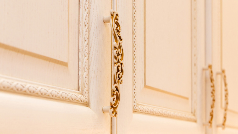 Cream cabinets with ornate gold hardware.