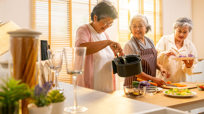 Three people cooking together in a large kitchen