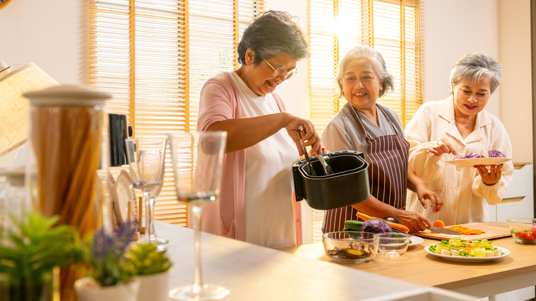 Three people cooking together in a large kitchen