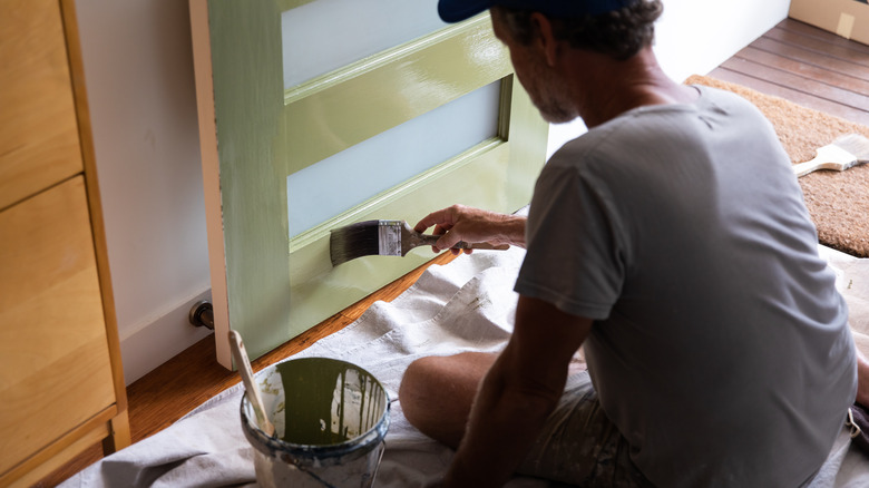 person painting door green 