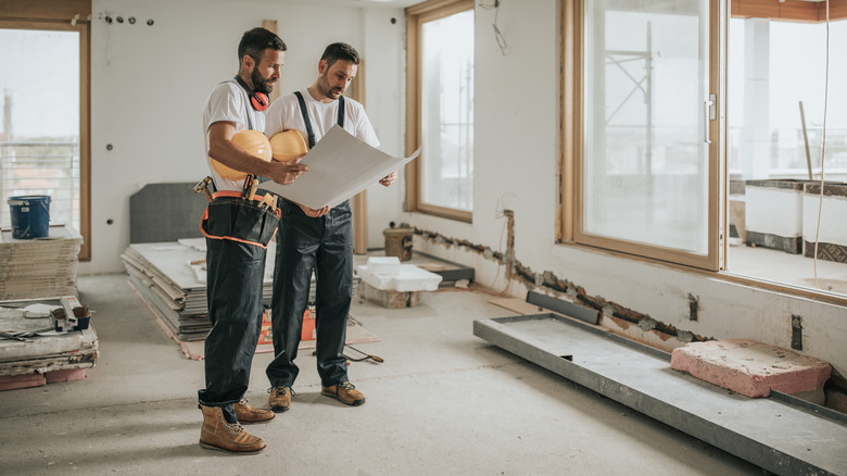 Two construction workers standing in an apartment building