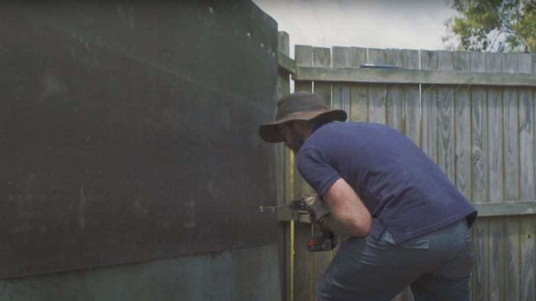 Man installing MLV to fence