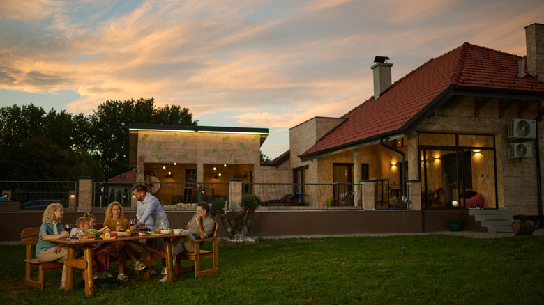 family having dinner in their yard with cozy patios behind them