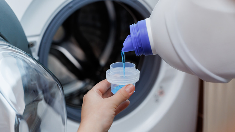 Person dumping laundry detergent into cup
