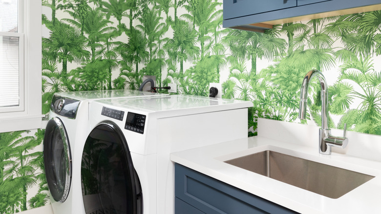 A laundry room with bold greenery-inspired wallpaper