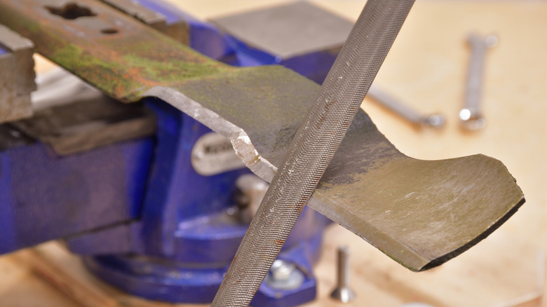 Sharpening a lawn mower blade with a file