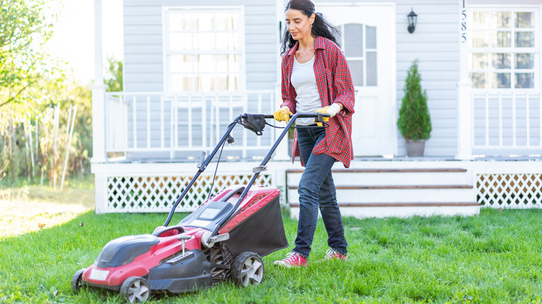 Woman pushes a contemporary lawn mower.
