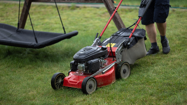 Man mowing grass while it rains
