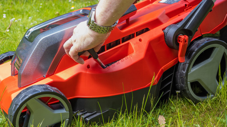 Male hands adjusting the cutting height on a lawn mower