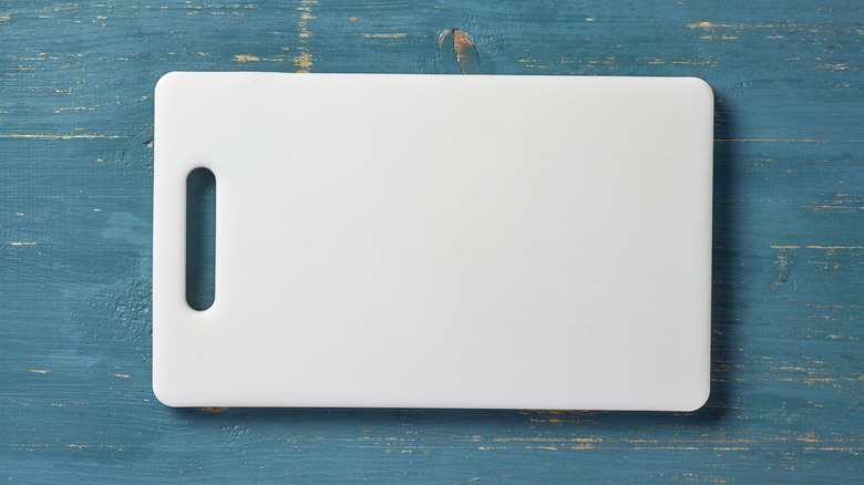 A white plastic cutting board on a blue wood table