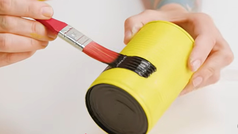 Person painting a tin can