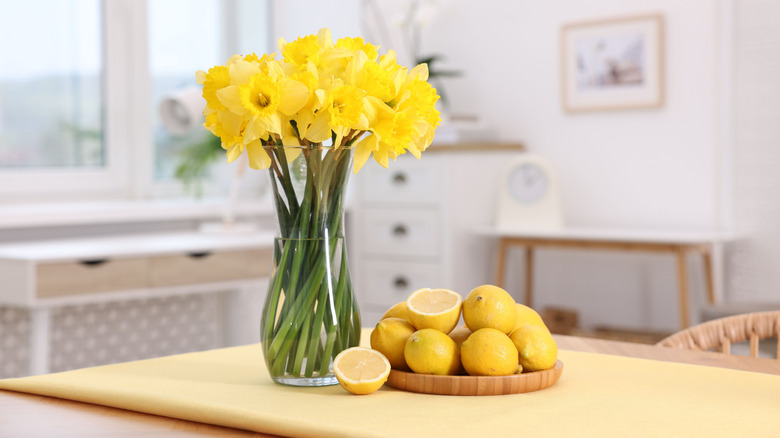 Lemons next to a vase of flowers