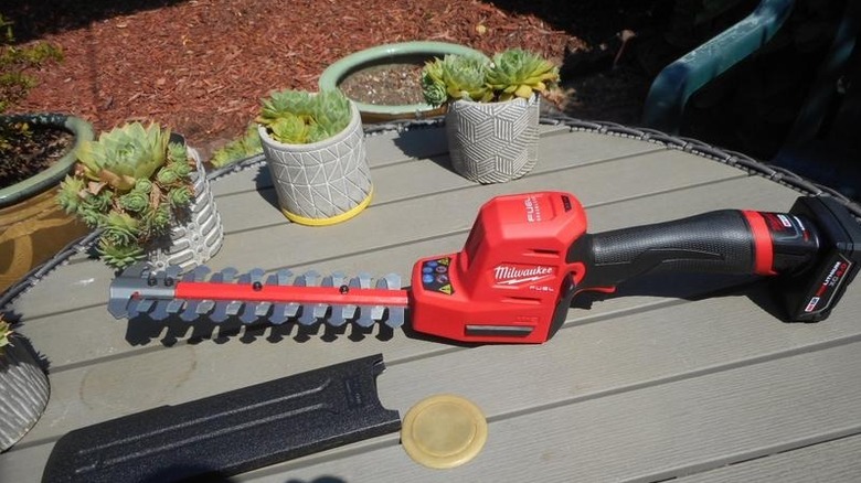 Milwaukee's M12 8-inch Lithium-Ion Cordless Brushless Hedge Trimmer on a garden table