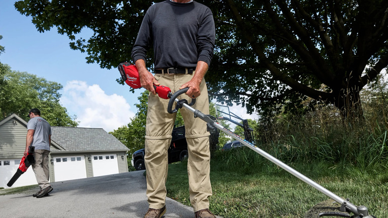 A gardener trimming driveway edge with Milwaukee's M18 16-inch Brushless Cordless QUIK-LOK String Trimmer