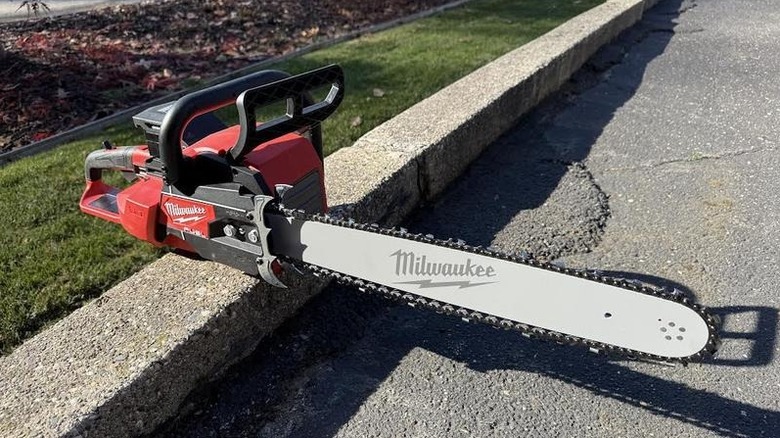 Milwaukee's M18 16-inch Lithium-Ion Brushless Cordless Chainsaw sitting on a stone driveway edge