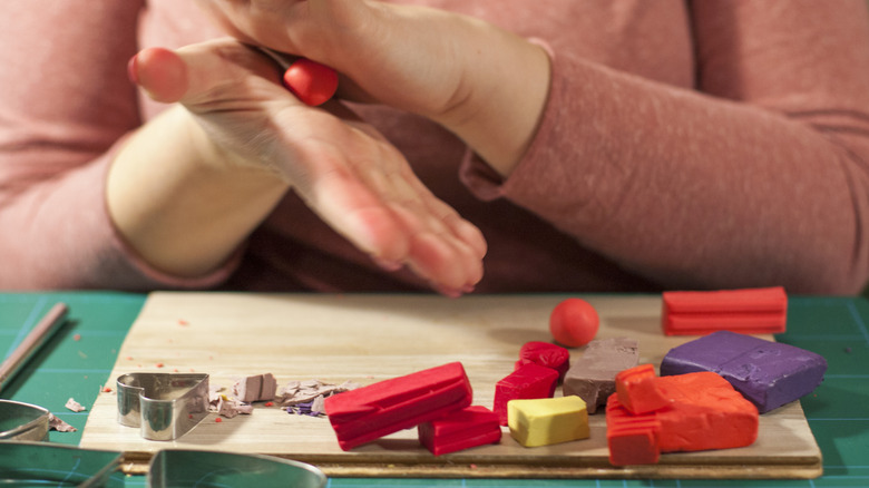 A person kneads colorful polymer clay before crafting.