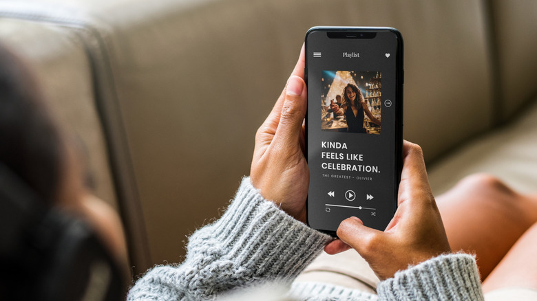 person turning on playlist from phone