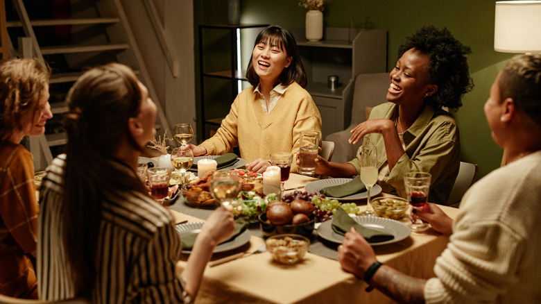 people at dinner party, laughing around table