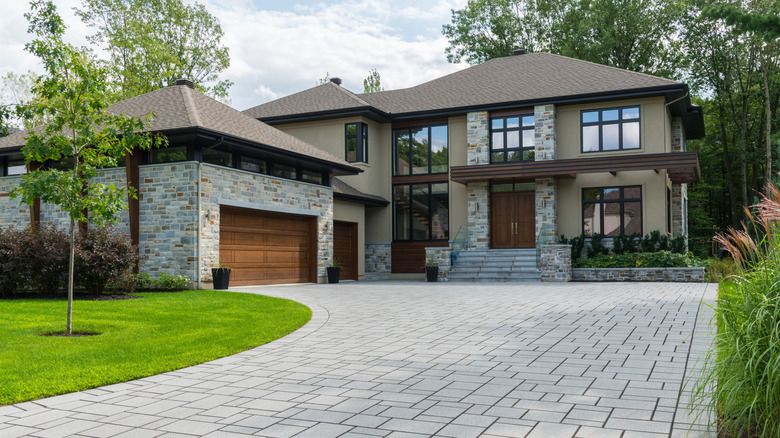 Modern home with interlocking paver driveway to a garage