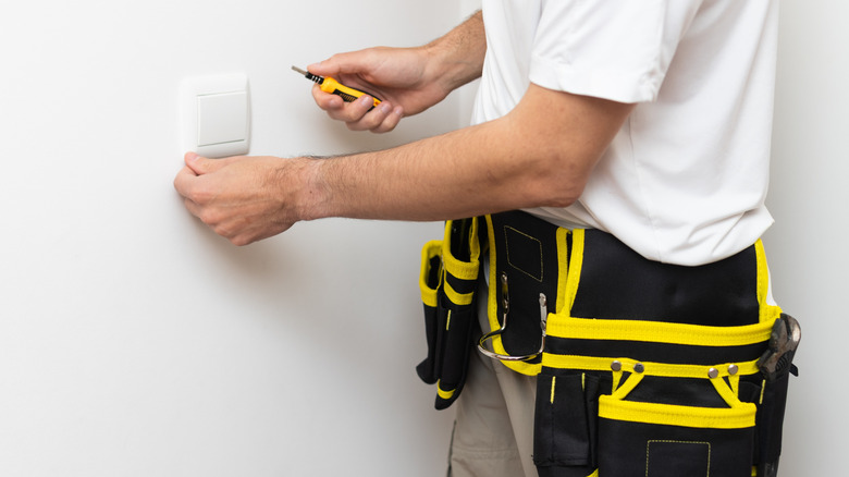Electrician installs lighting switch in the wall
