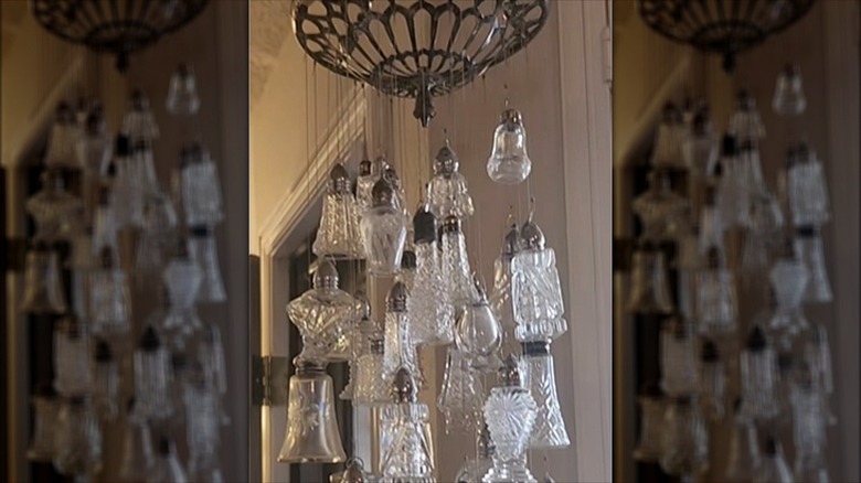 Many empty cut glass salt and pepper shakers hang from a repurposed light fixture.