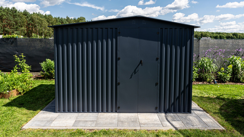 A metal storage shed sitting in a backyard.