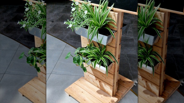 Light colored wood stand with two metal planters hanging on it.
