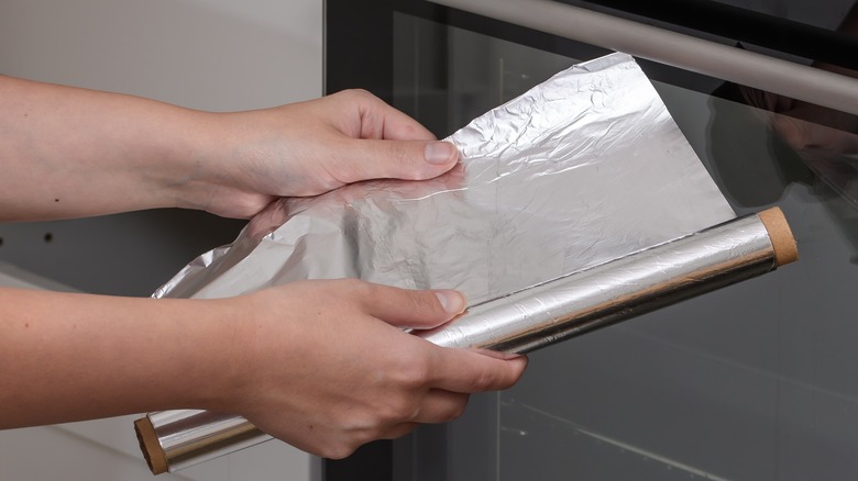 hands holding aluminum foil roll 