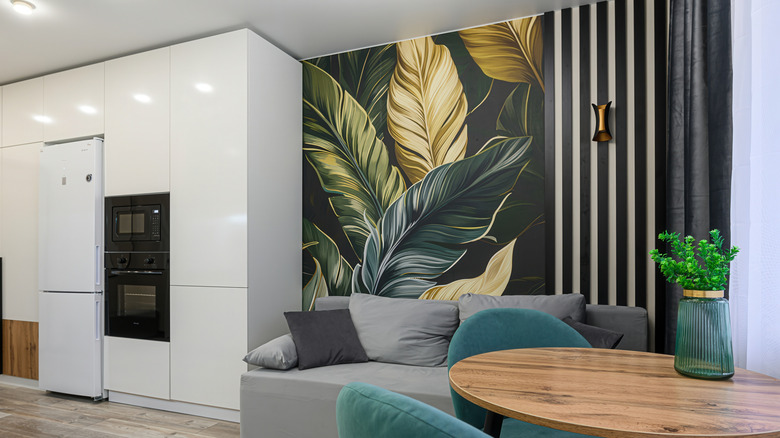 An open-plan living area with an accent wall featuring botanical wallpaper