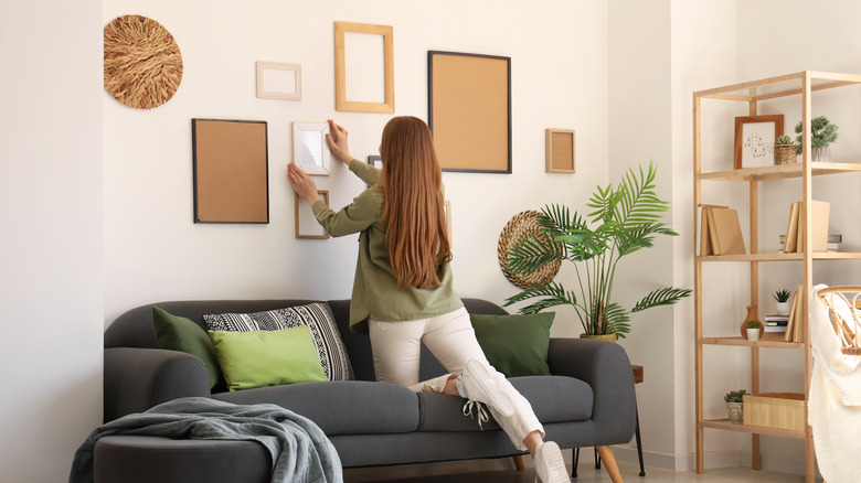 A person hanging pictures to create a gallery wall in their living room