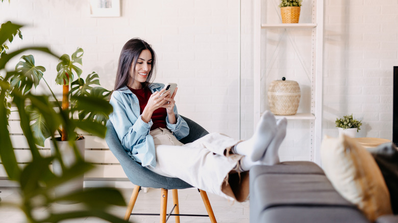 A person relaxing in their living room and scrolling on their phone
