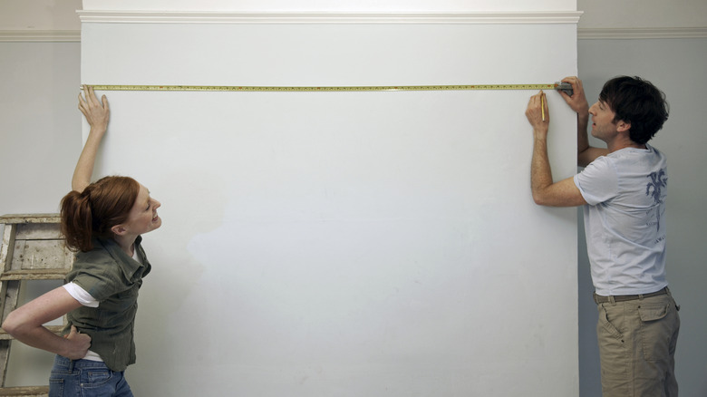 Couple measuring a blank wall