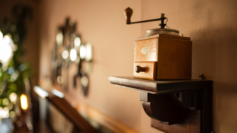 A wood, wall-mounted vintage coffee grinder.