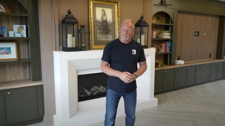 Mike Holmes standing in front of a white fireplace.