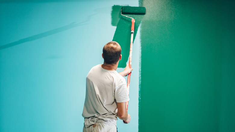 A man painting a wall with a roller