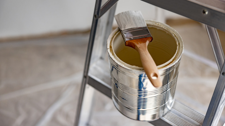 An open can of paint sitting on a ladder