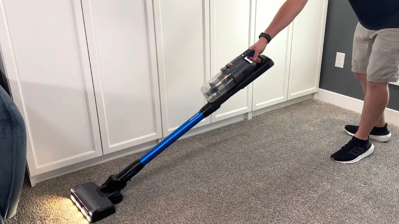 Person using BISSELL PowerClean FurFinder stick vacuum on carpet