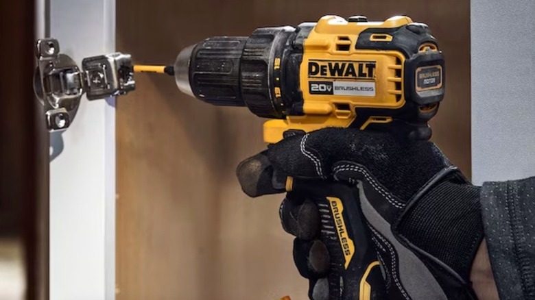 Person using DEWALT 20V drill to attach door hinge