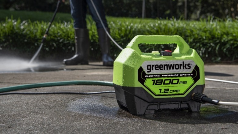 Person pressure washing driveway with Greenworks 1800-PSI