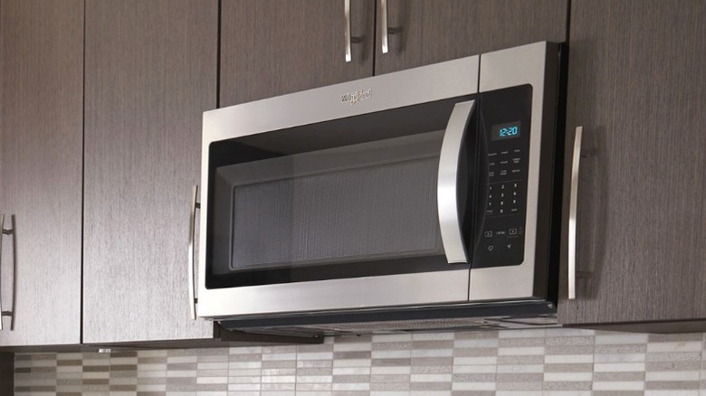 Whirlpool WMH31017HZ OTR over kitchen range under dark wood cabinets