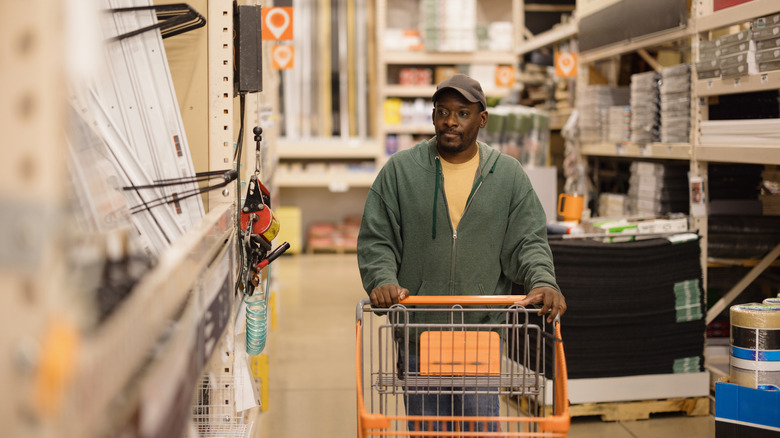 A man pushing a shopping cart in a home improvement store